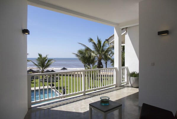 Ein Balkon mit Blick auf den Ozean, ein Pool und Palmen.