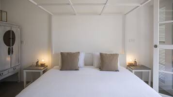 Ein Hotelzimmer mit einem großen Bett, zwei Nachttischen mit Lampen, einem Kleiderschrank und einer Tür mit Jalousien.