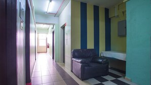 A hallway with a checkered floor, a black leather sofa, and a table with a white tablecloth. - Hotel O Casavilla Hotel (Batu Caves)
