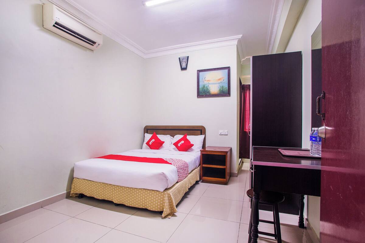 A clean, well-lit room with a bed, a desk, and a mirror.
