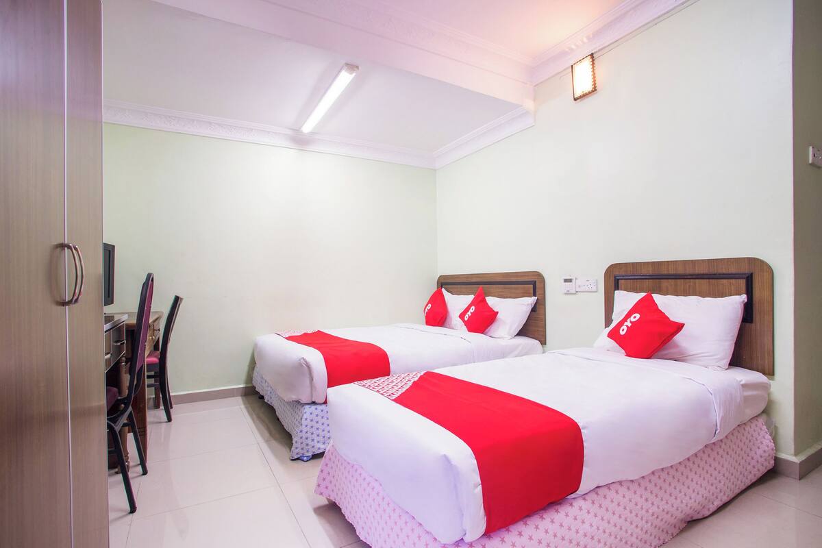 A hotel room with two beds, a desk, and chairs.
