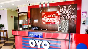 A reception desk with a red and blue design, a clock, and a flower vase. - Hotel O Casavilla Hotel (Batu Caves)