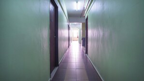 A long, narrow hallway with green walls and a tiled floor, leading to a bright room at the end. - Hotel O Casavilla Hotel (Batu Caves)