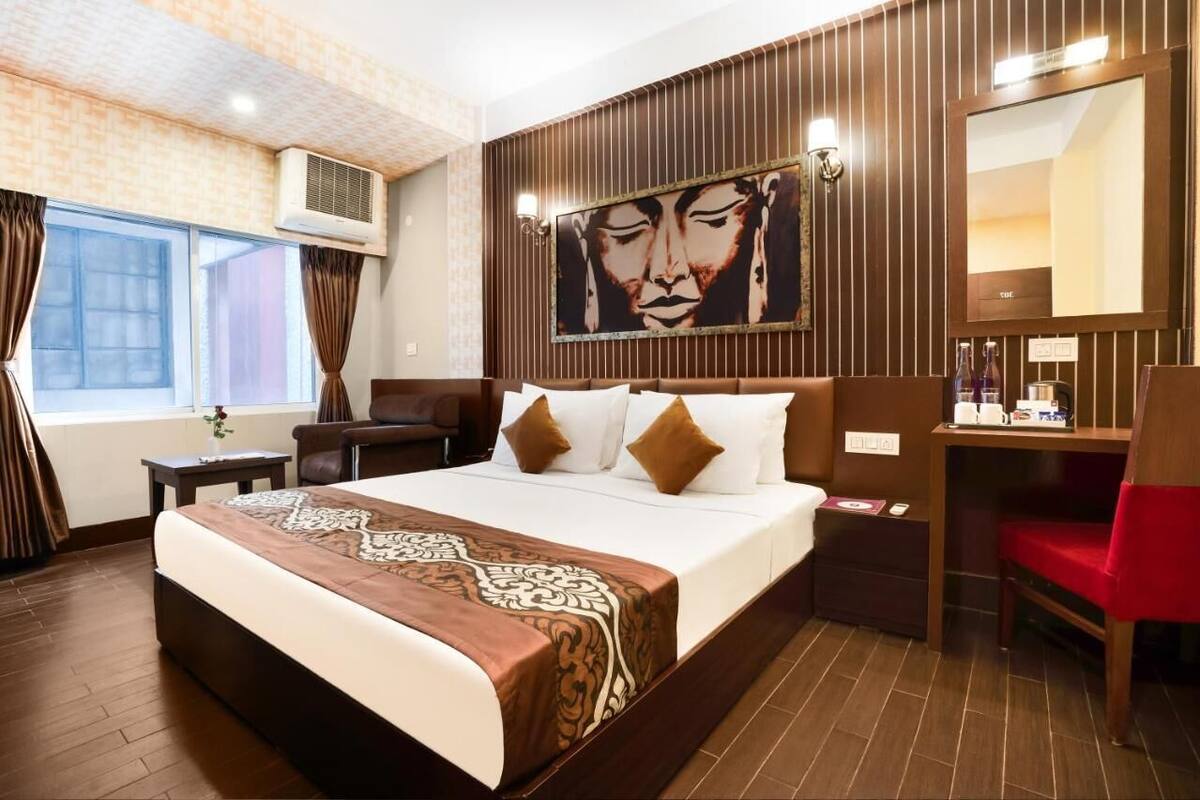 Une chambre d’hôtel avec un grand lit, un bureau, une chaise, un miroir et un tableau au mur.