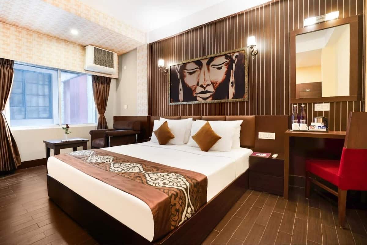 Una habitación de hotel con una cama grande, un escritorio, una silla, un espejo y un cuadro en la pared.