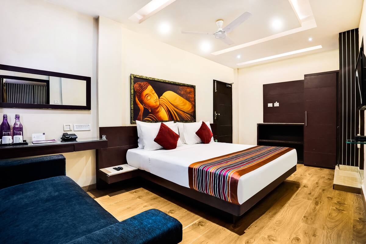 Une chambre d’hôtel moderne avec un grand lit, un bureau équipé d’un ordinateur, une chaise et une armoire.