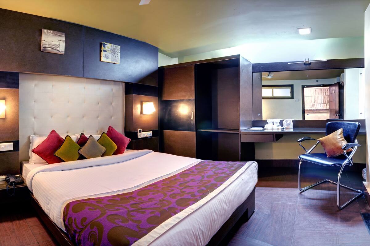 Une chambre d’hôtel comprenant un lit, des tables de chevet, un bureau, une chaise et un miroir.