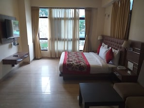 A hotel room with a bed, a TV mounted on the wall, a bedside table, a nightstand, and a window with curtains. - Sobralia Hotels Casino Resort & Spa (Namchi)