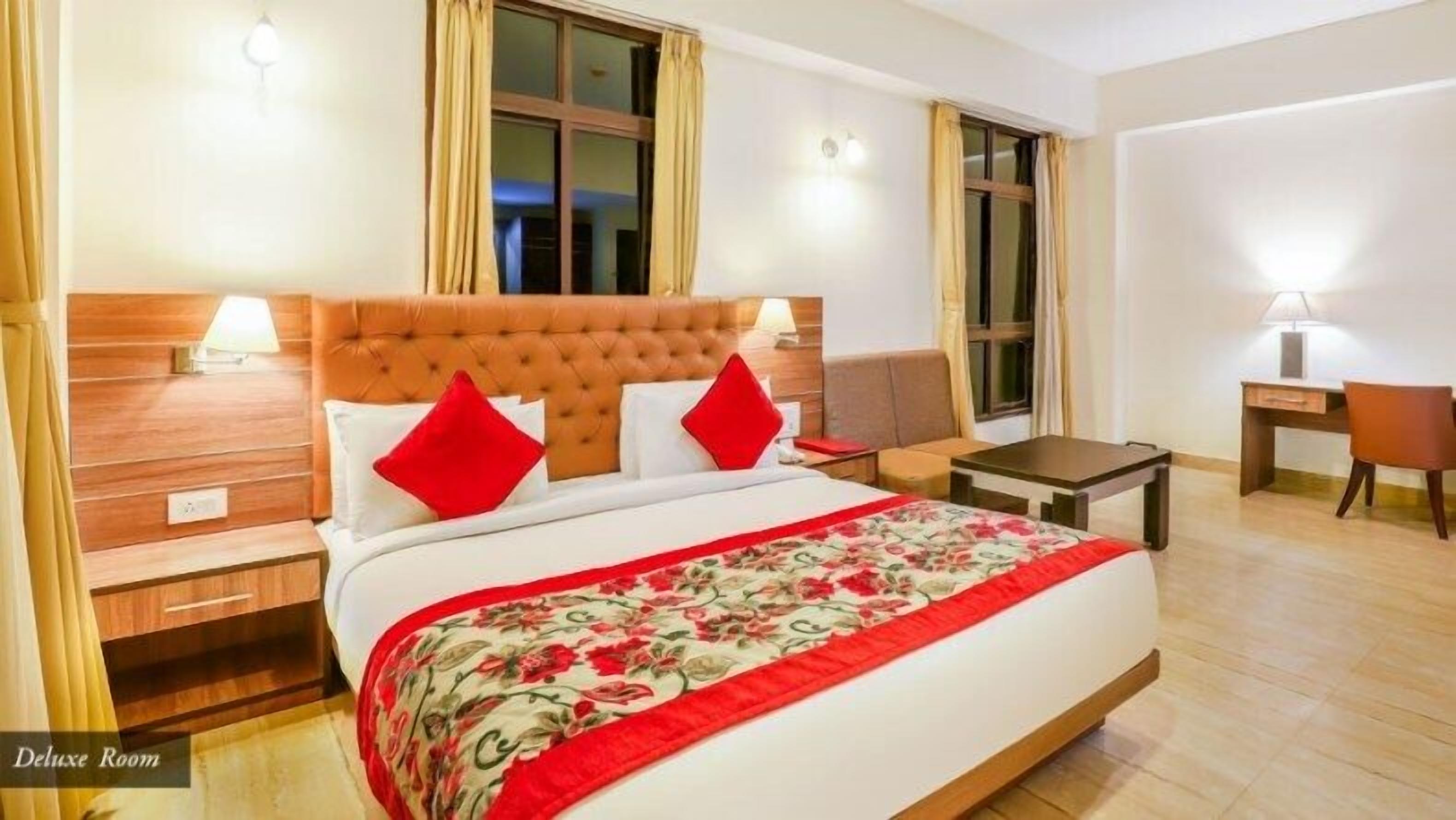 Een Deluxe kamer met een groot bed, twee nachtkastjes, een bureau en een stoel.