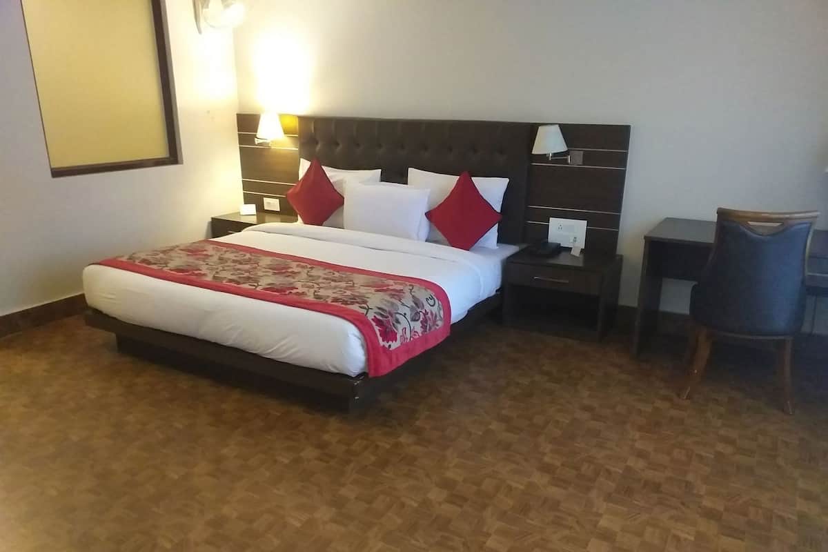 Ein Hotelzimmer mit Bett, Nachttischen, Schreibtisch und Stuhl.