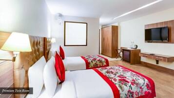 A hotel room with two beds, a TV, a desk, and a wardrobe.