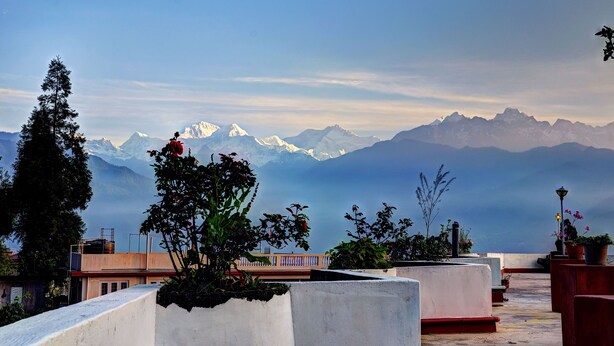 A rooftop terrace with a view of snow-capped mountains, potted plants, and a lamp post. - Summit Newa Regency (Gyalshing)