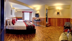 A hotel room with two beds, a television, a small table, and a wooden floor. - Summit Newa Regency (Gyalshing)