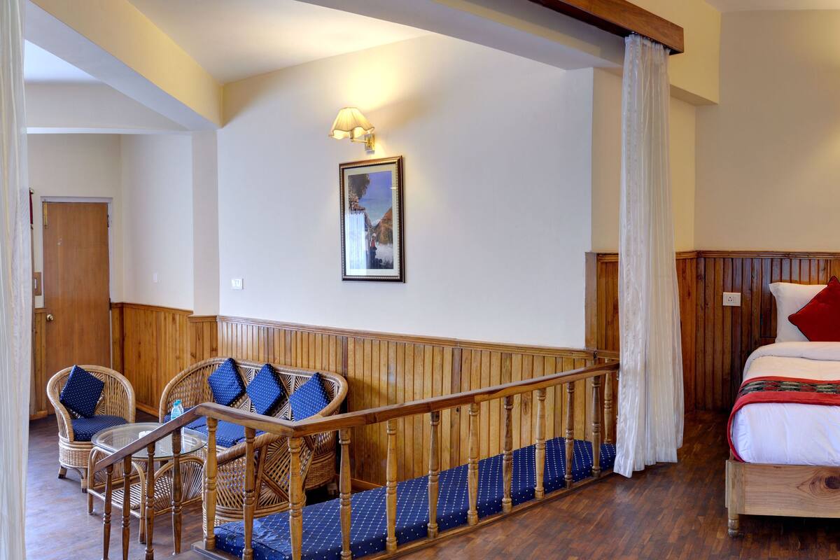 Une chambre avec un lit en bois, des oreillers rouges et blancs, un canapé à motifs bleus et blancs, et un plancher en bois.