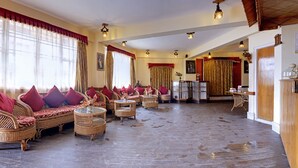 A spacious room with wicker furniture, red cushions, and a glass coffee table. - Summit Newa Regency (Gyalshing)