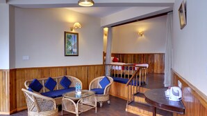 A room with a wooden bench, wicker furniture, and a table with a kettle. - Summit Newa Regency (Gyalshing)