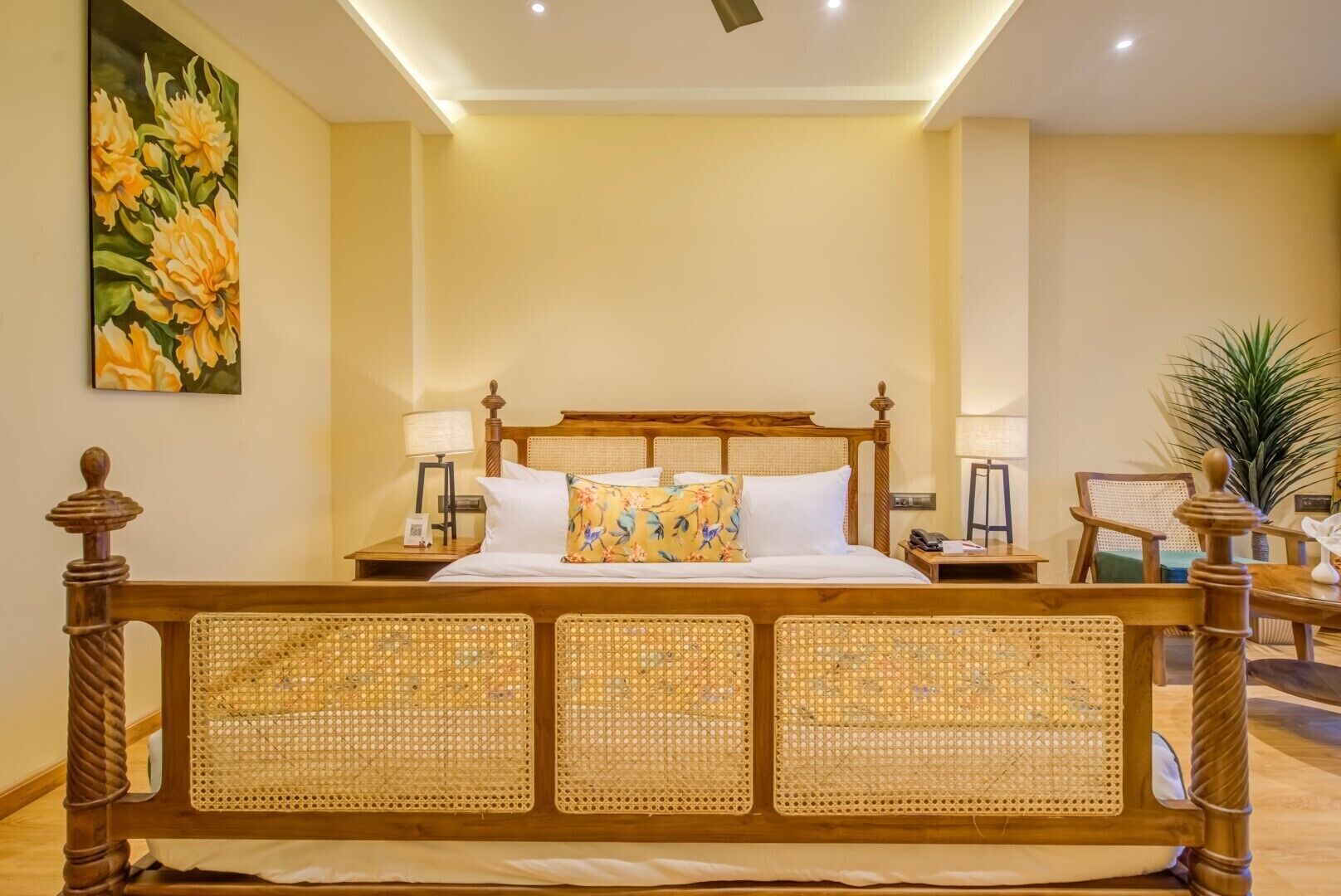 Una habitación con una cama grande, dos mesitas de noche, un cuadro y una planta en maceta.