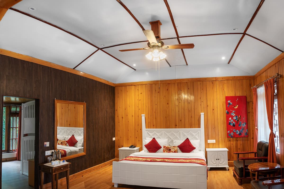 Un dormitorio amplio con una cama grande, paredes de madera, un ventilador de techo y un cuadro en la pared.