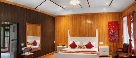 Un dormitorio amplio con una cama grande, paredes de madera, un ventilador de techo y un cuadro en la pared.