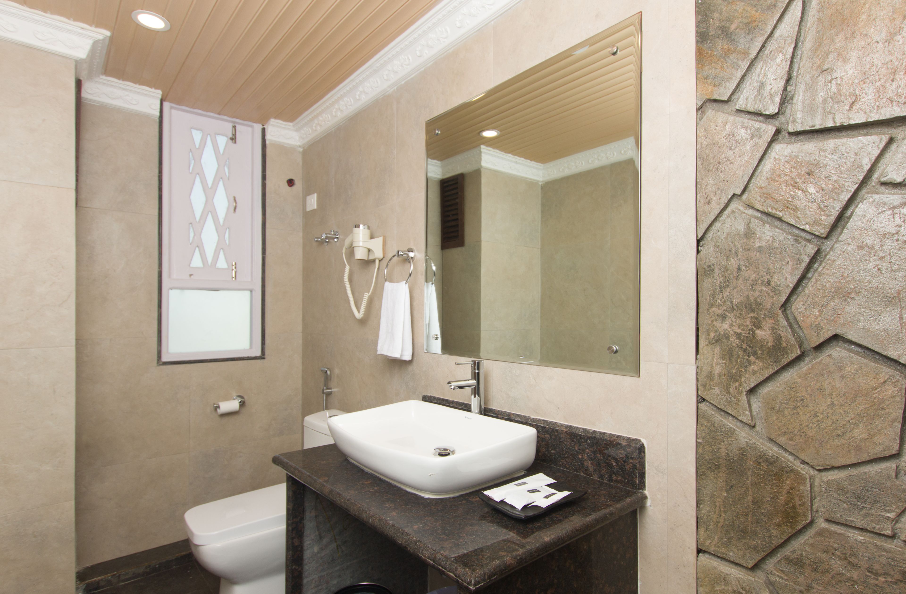 A bathroom with a white sink, a mirror, a towel ring, and a toilet.