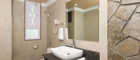 A bathroom with a white sink, a mirror, a towel ring, and a toilet.