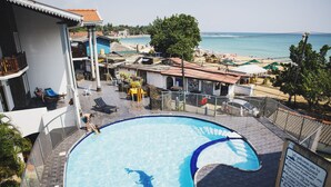 A swimming pool with a clear view of the beach and ocean in the background. - Neptune Bay Hotel (Unawatuna)
