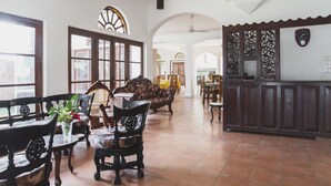 A spacious living area with a large window, wooden furniture, and a decorative wall panel. - Neptune Bay Hotel (Unawatuna)