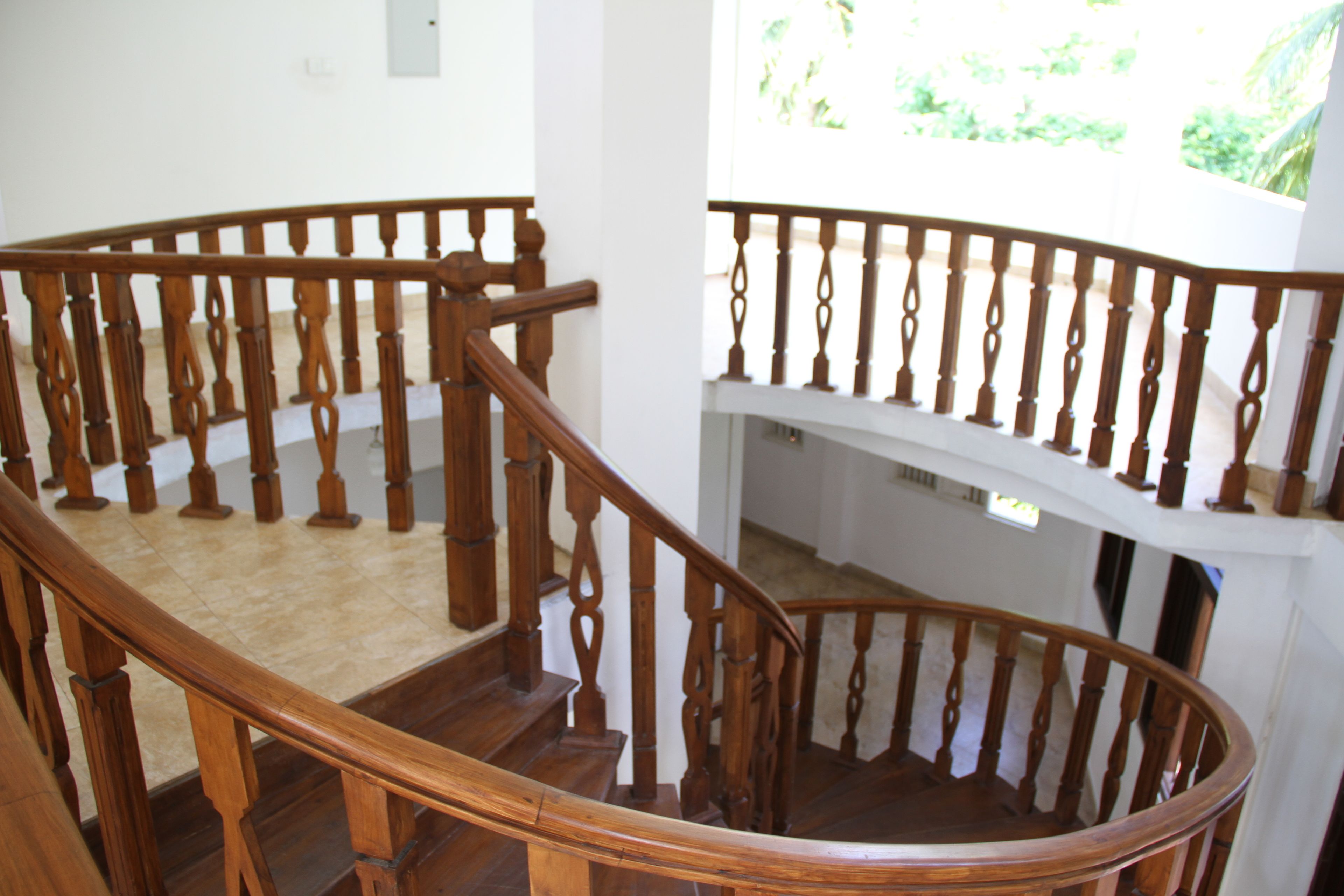 Una escalera de madera con diseño curvo y barandilla blanca.