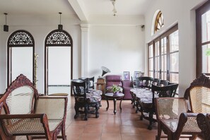 A traditional room with wooden furniture, a purple armchair, and large windows. - Neptune Bay Hotel (Unawatuna)