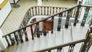 A multi-level interior with a curved staircase, a wooden door, and patterned flooring. - Neptune Bay Hotel (Unawatuna)