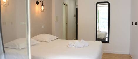 Quarto de hotel com cama, espelho e arandelas.