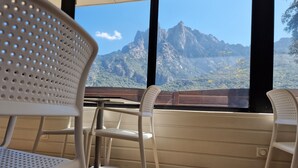 Vista desde una ventana mostrando un paisaje montañoso, incluyendo un pico destacado, a través de un marco de madera.