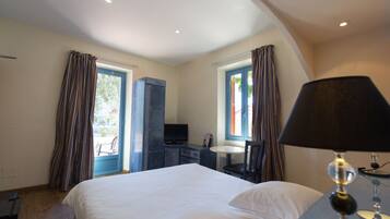 A hotel room with a bed, a desk, a chair, a television, and a window with curtains.