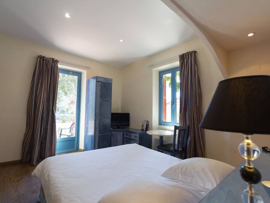 A hotel room with a bed, a desk, a chair, a television, and a window with curtains.