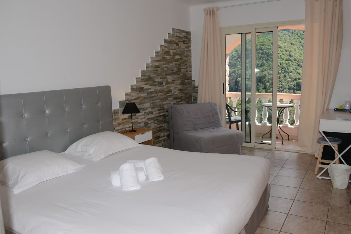 Habitación de hotel con cama, una silla, un escritorio y vistas a un balcón con mesa y sillas.