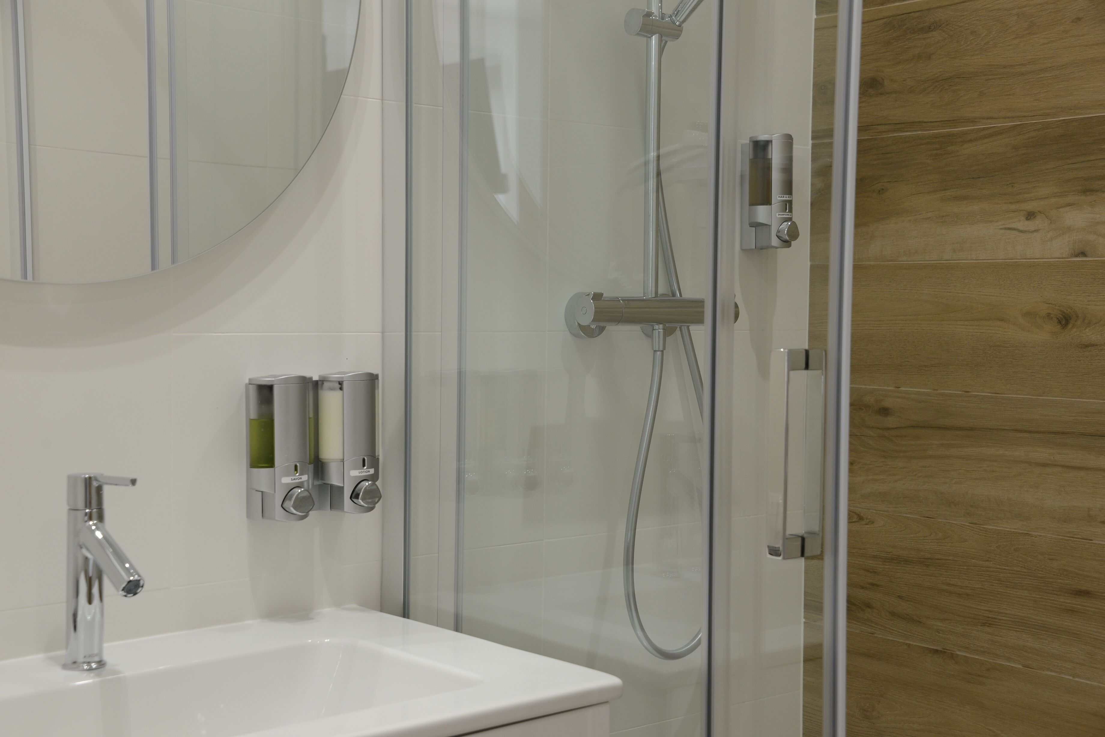 Un baño moderno con cabina de ducha de vidrio, un lavabo blanco y un espejo encima.