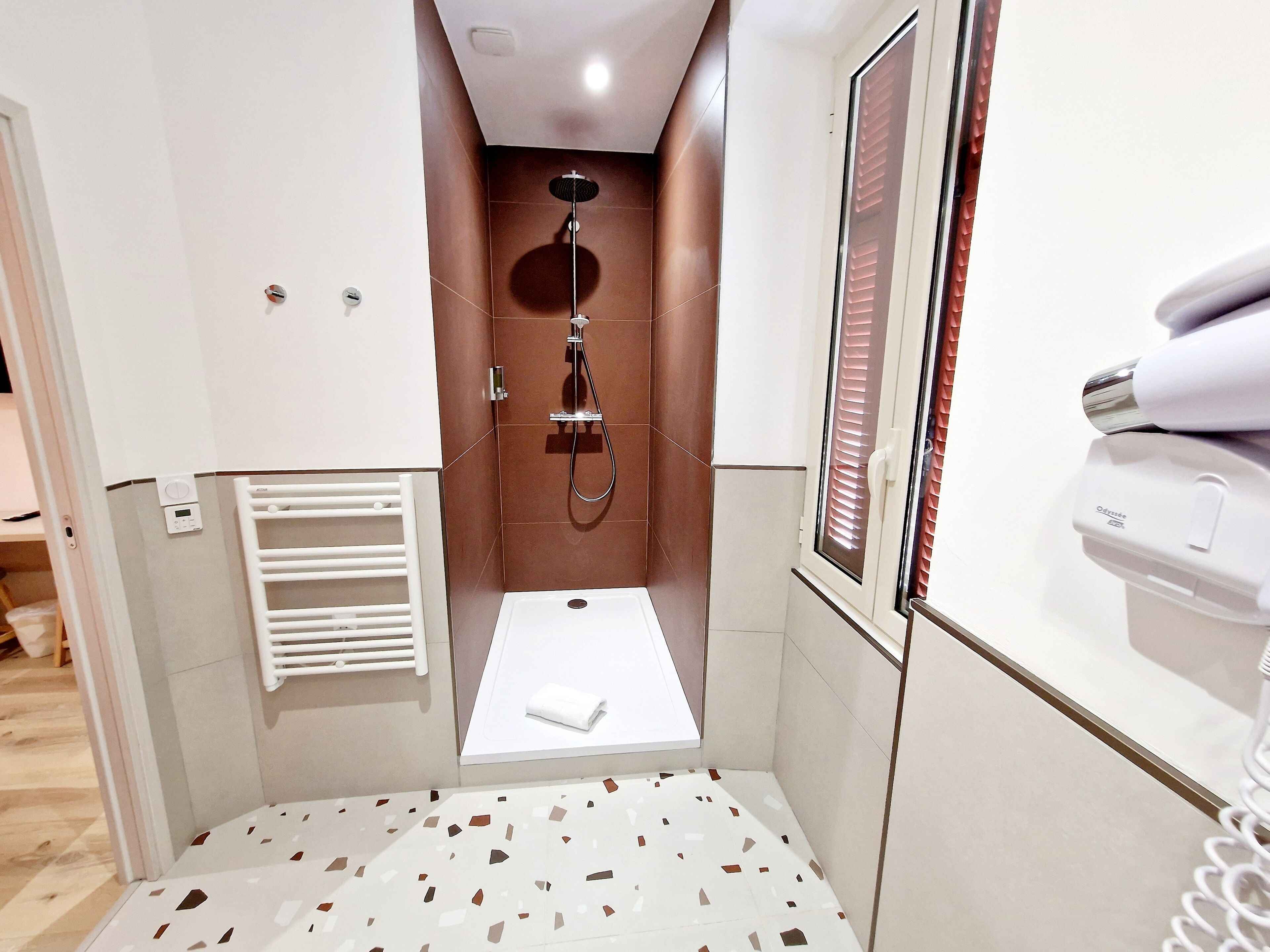 Un baño pequeño con ducha, inodoro y un perchero para toallas.