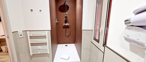 Un baño pequeño con ducha, inodoro y un perchero para toallas.
