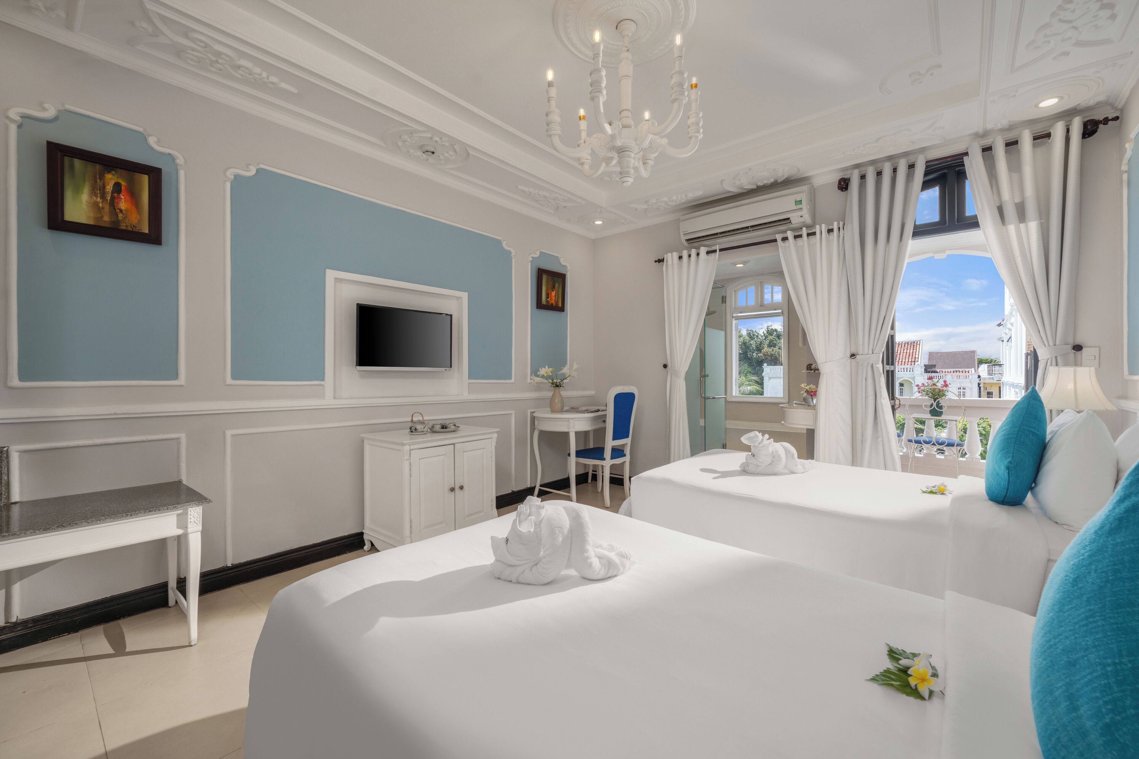 Une chambre d’hôtel avec deux lits, un bureau, une télévision et une vue sur l’extérieur.
