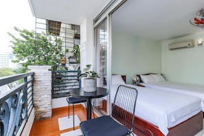 Een balkon met een tafel, stoelen, een bed en een bloempot.