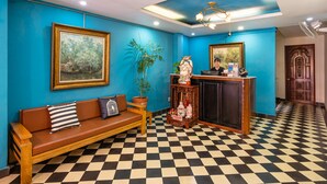 Un área de recepción con suelo a cuadros, un mostrador de madera, un sofá con cojines y dos cuadros enmarcados en las paredes.