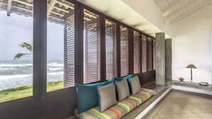 A seating area with a view of the ocean, featuring a bench with cushions and a lamp. - The Frangipani Tree By Edwards Collection (Unawatuna)