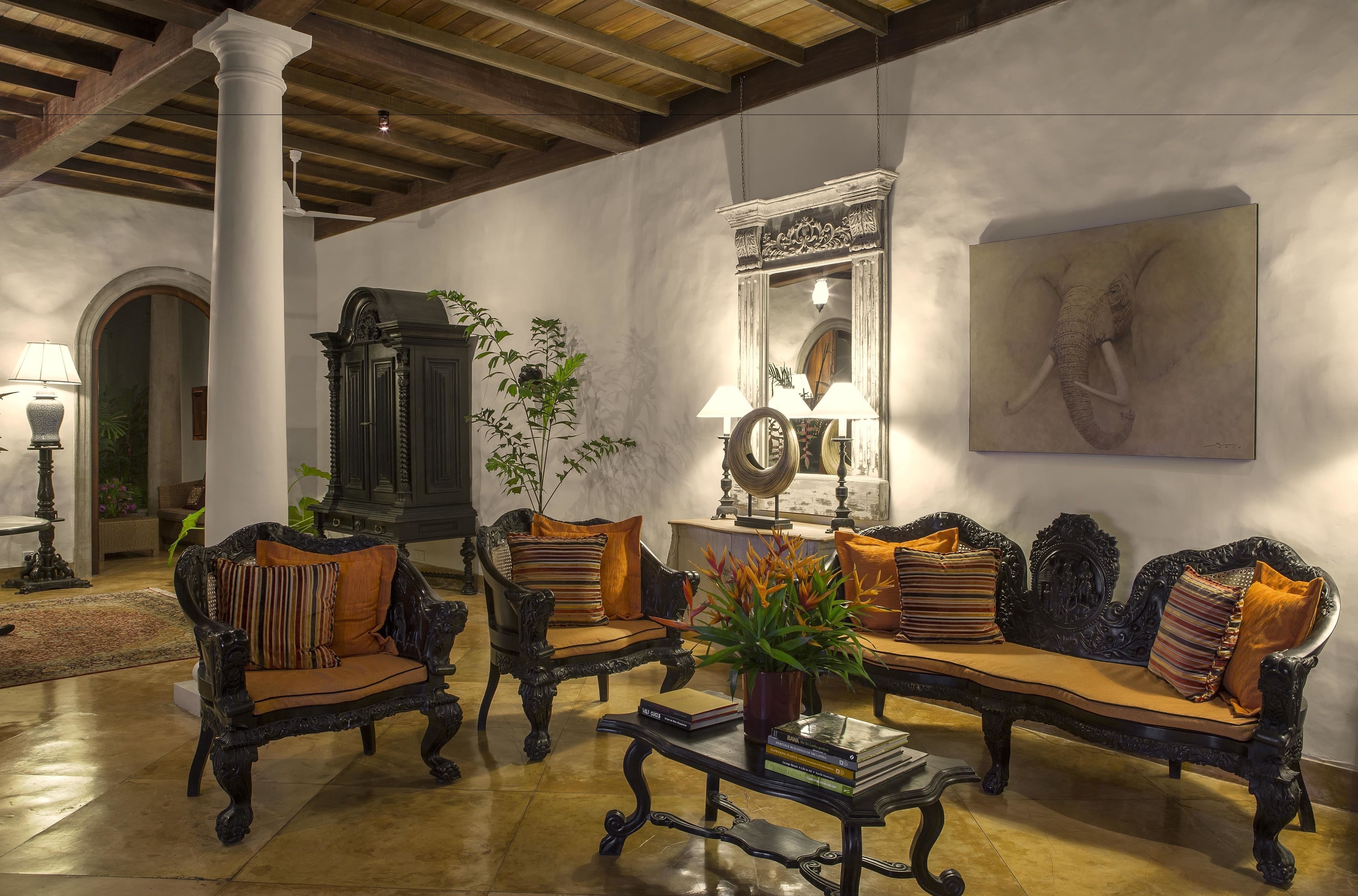 A spacious living room with ornate furniture, a large mirror, and a framed artwork on the wall.