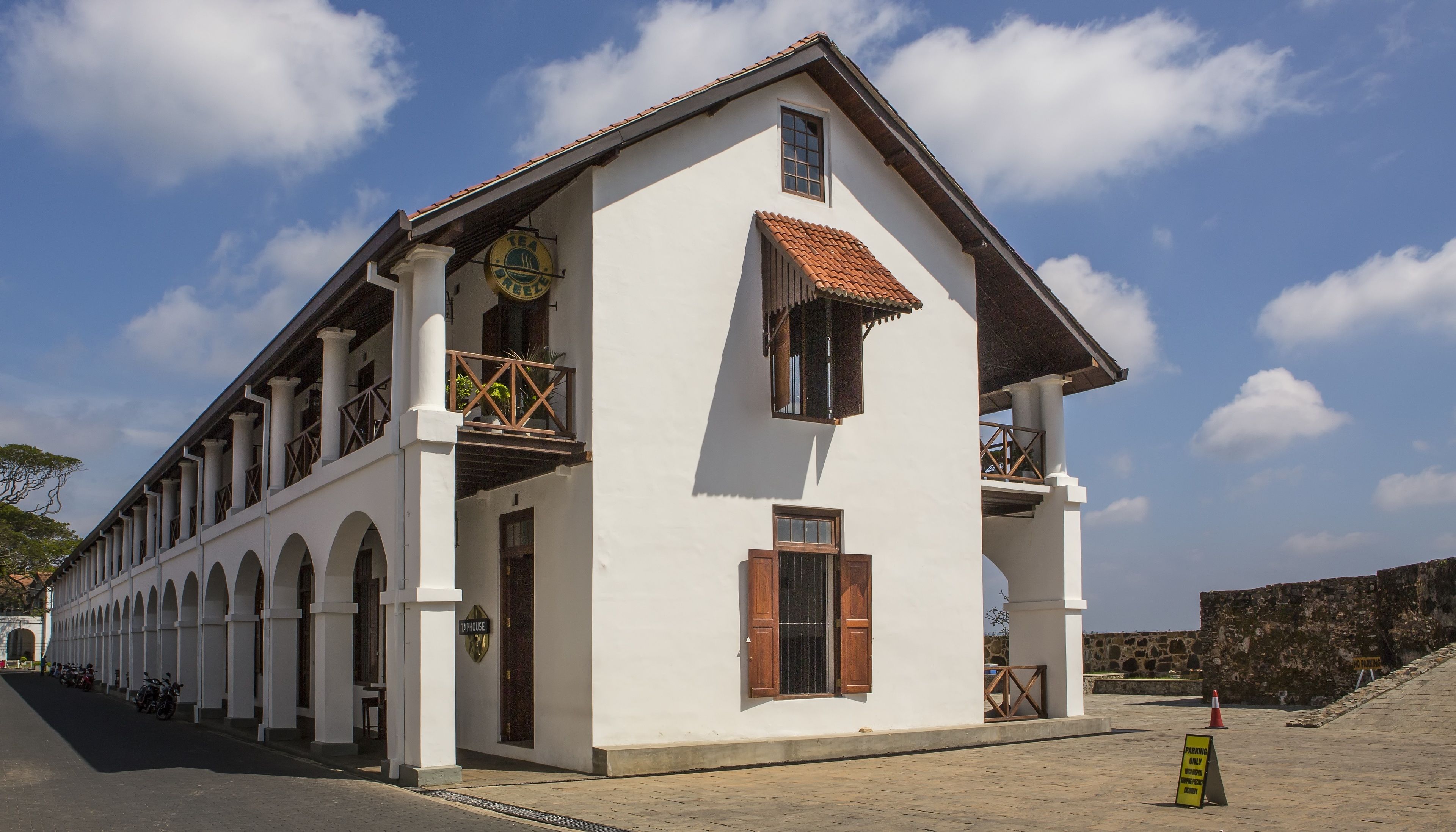 A white building with a tiled roof, arched windows, and a balcony.