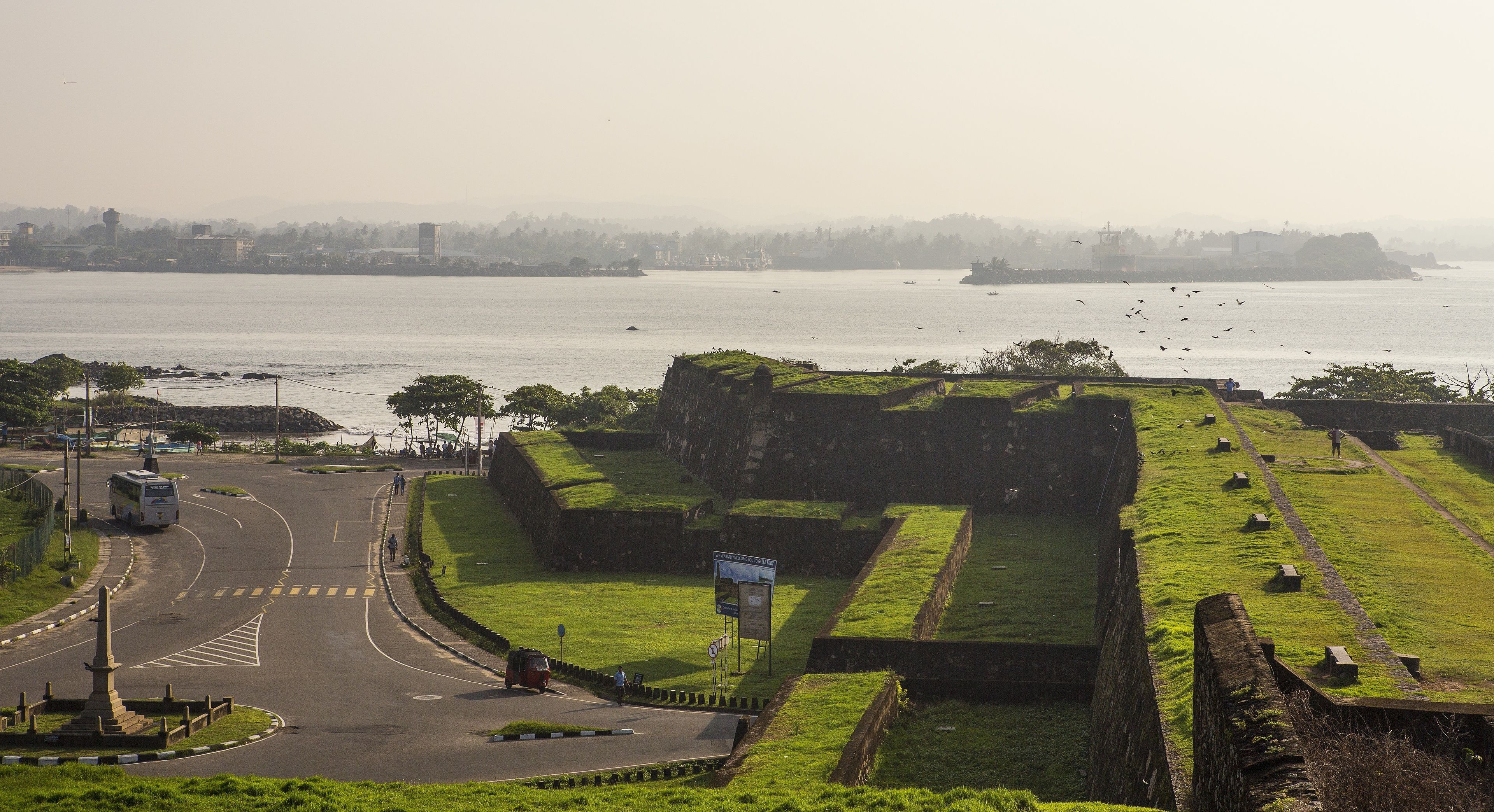 A coastal fort with green grass and a road leading to it.