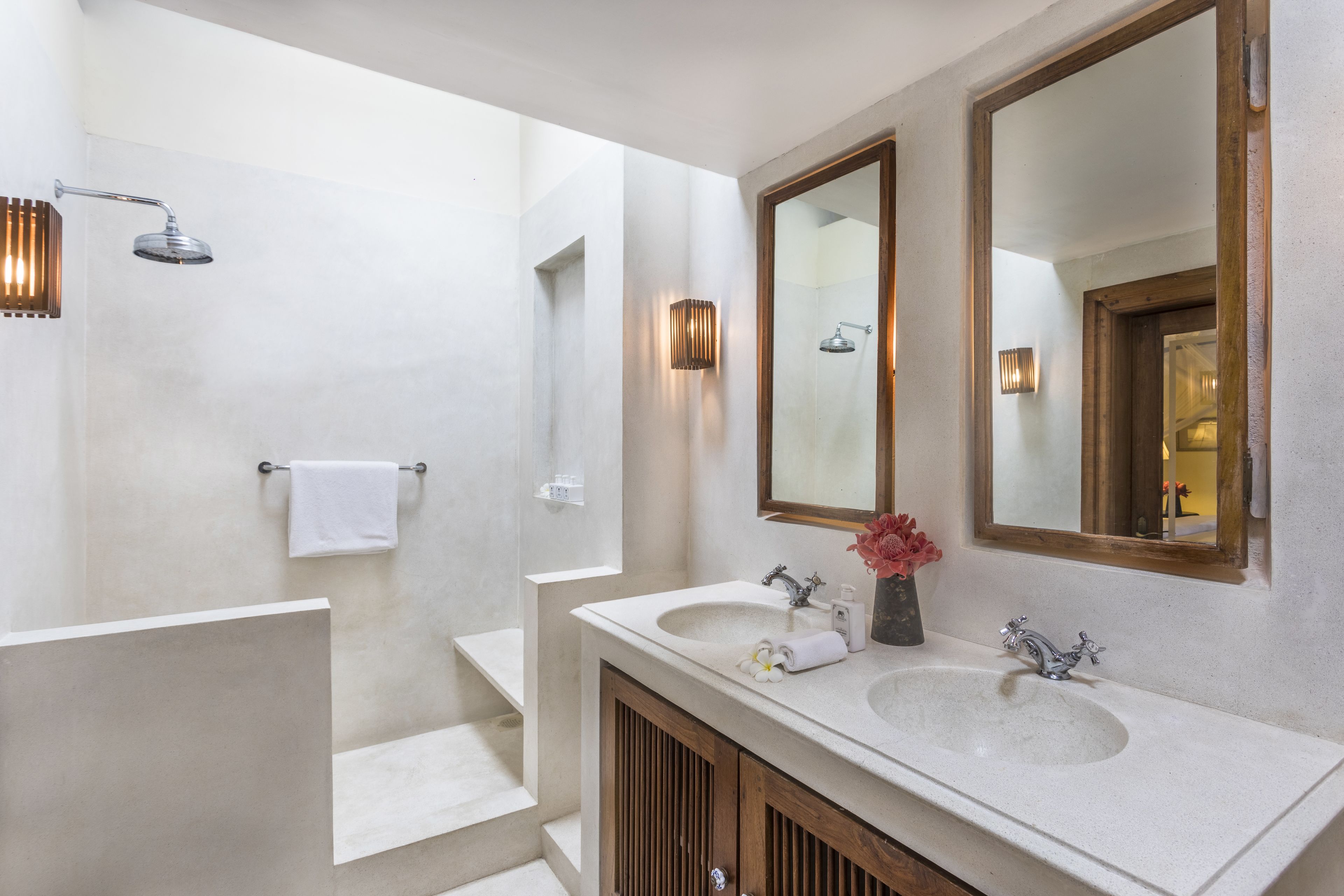 Un baño moderno con un espejo grande, dos lavamanos y una ducha.