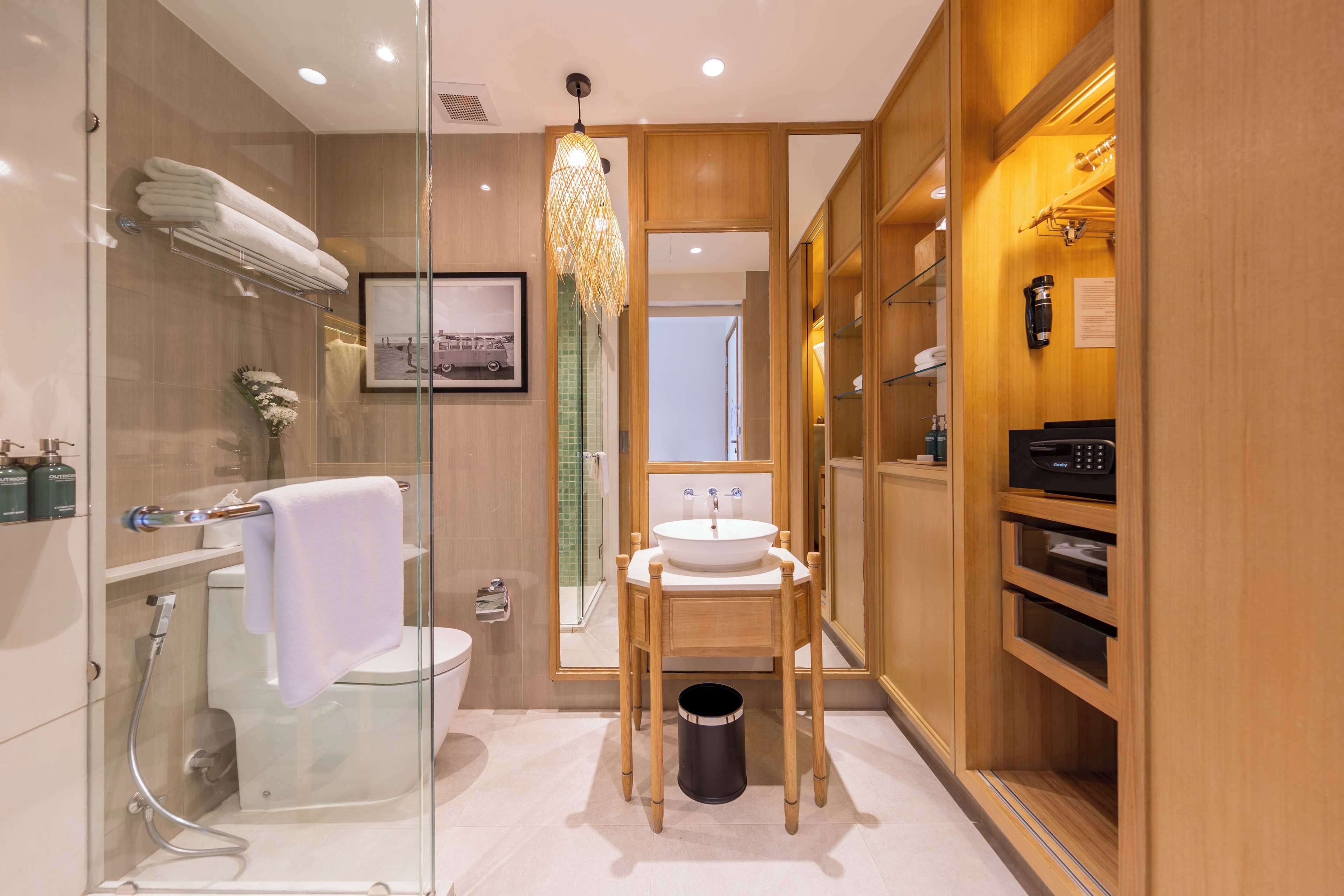 Un baño moderno con cabina de ducha de vidrio, tocador de madera con lavabo y un perchero para toallas.