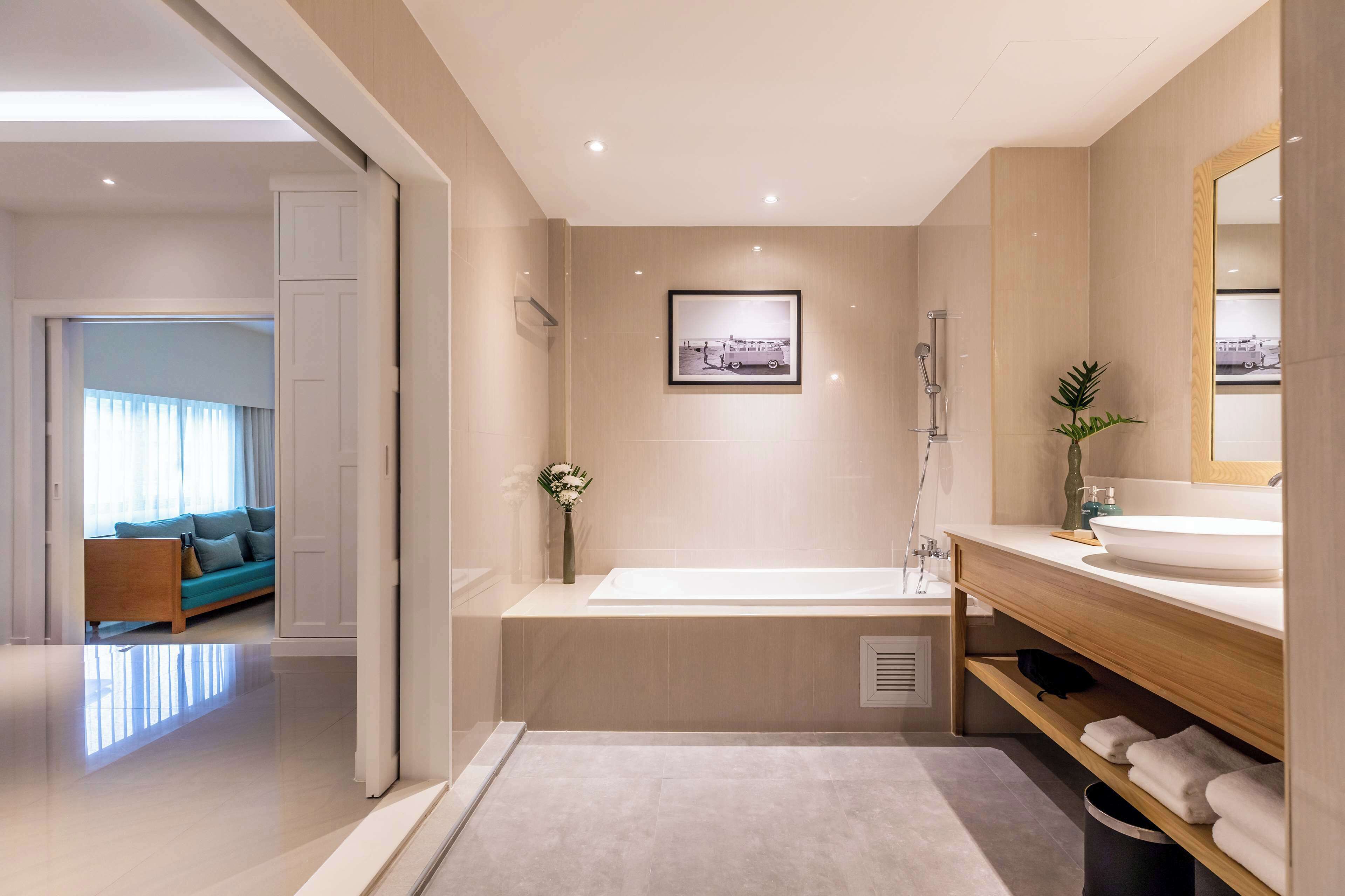 A modern bathroom with a bathtub, a large mirror, and a sink.