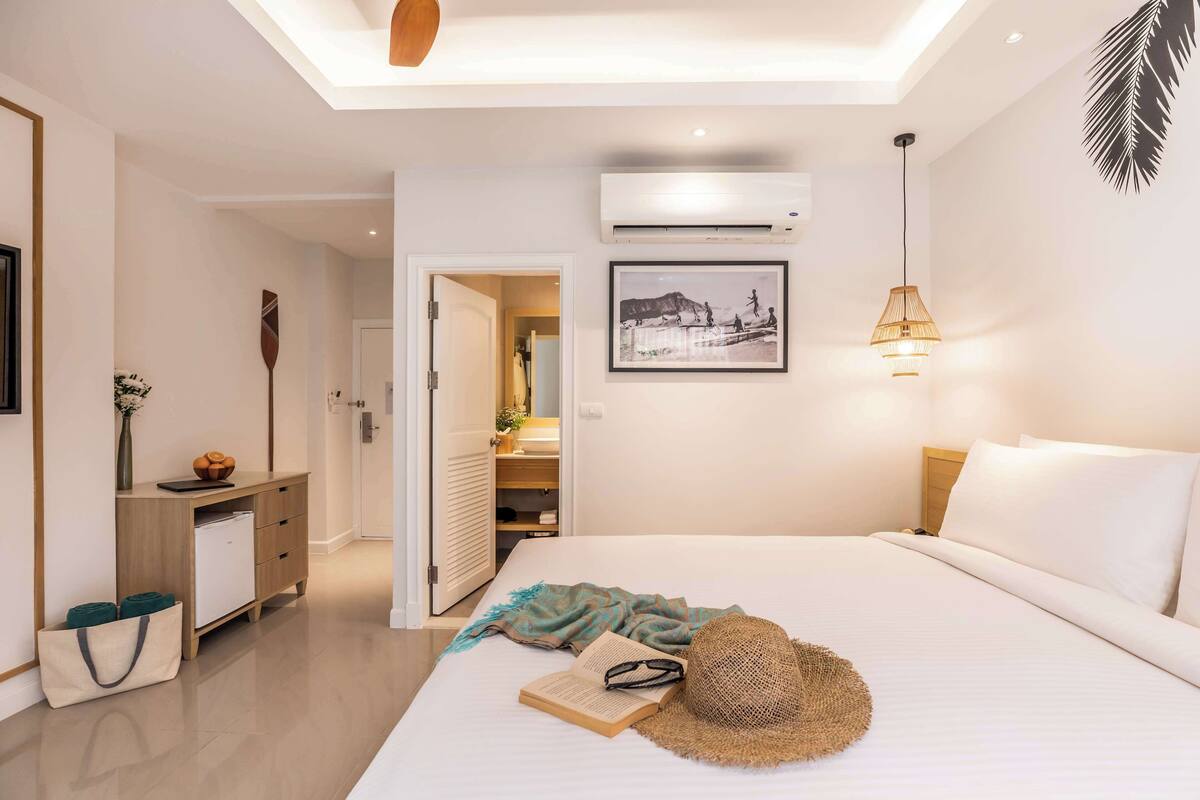 Una habitación de hotel moderna con una cama, un escritorio, un armario y un equipo de aire acondicionado.