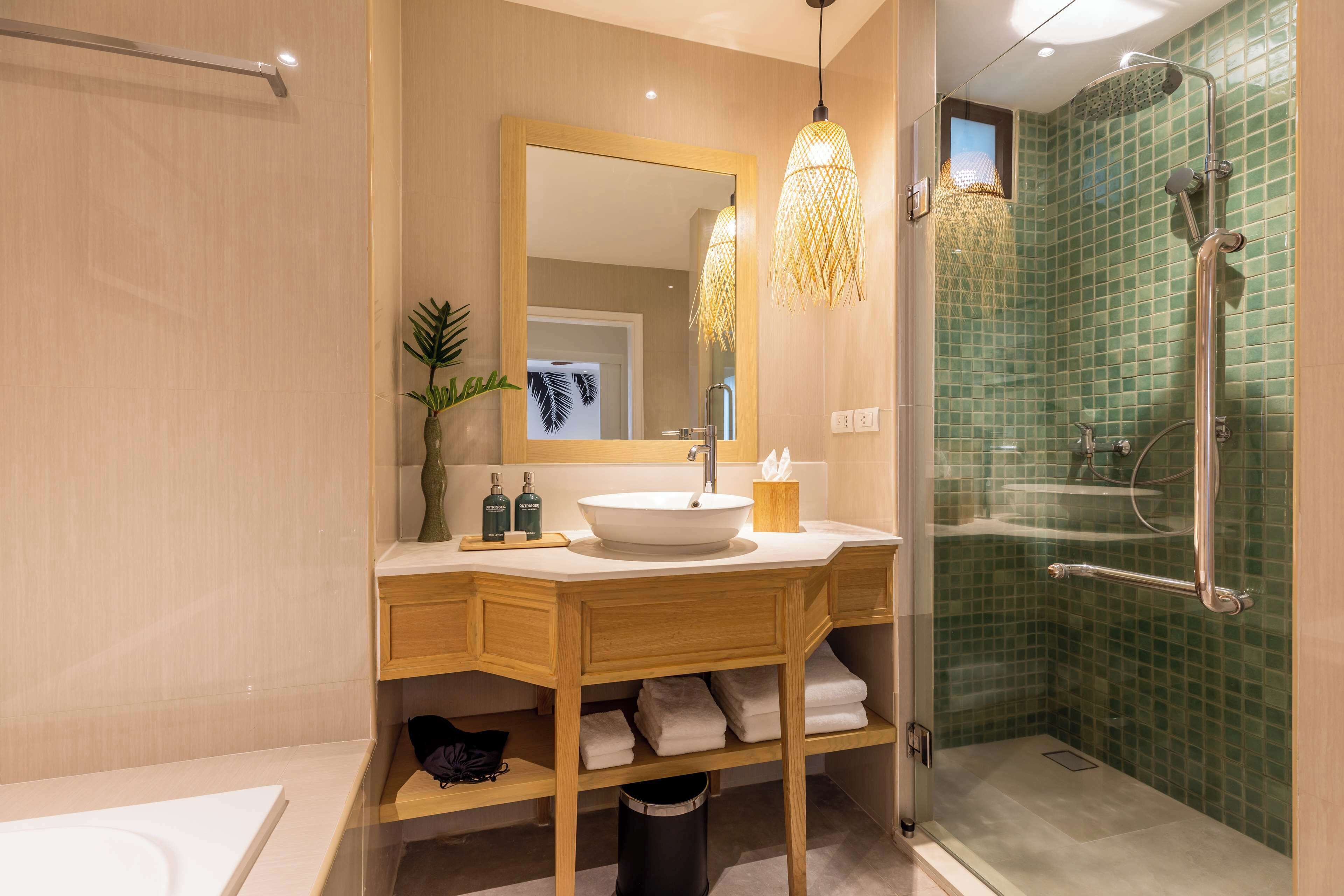 A modern bathroom with a wooden vanity, a large mirror, a white sink, and a glass shower enclosure.